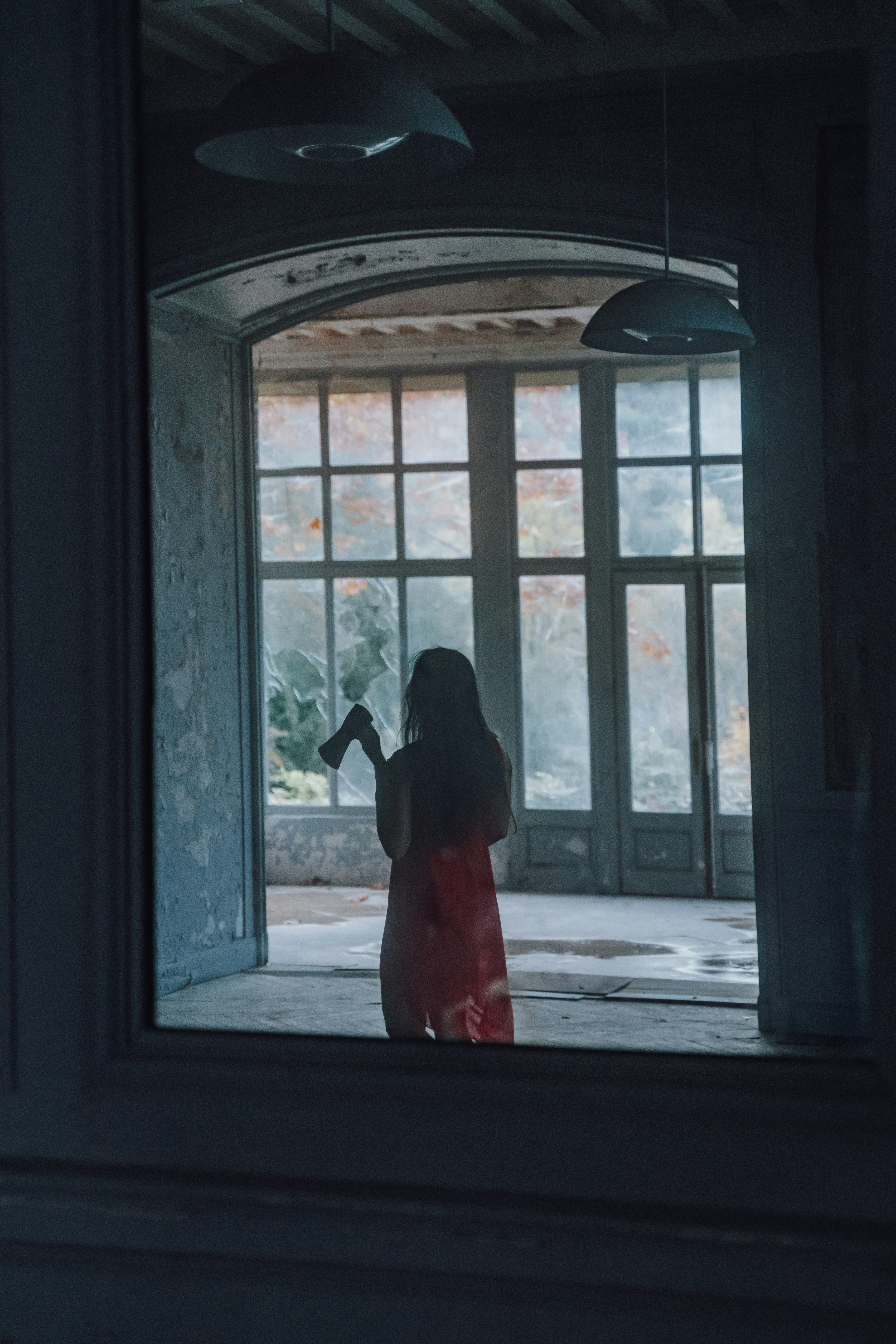 woman in red dress standing in front of window